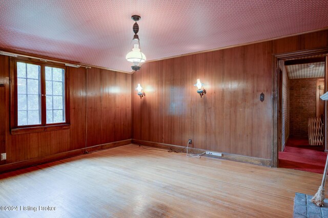 empty room with wooden walls, radiator, baseboards, and wood finished floors