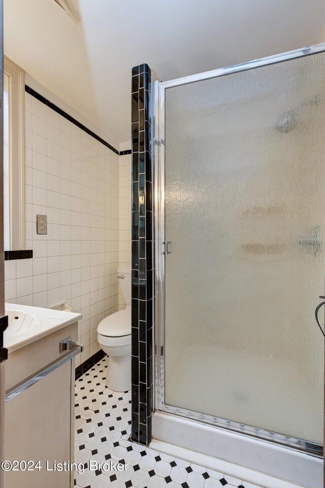 full bathroom featuring vanity, tile walls, a shower stall, and toilet