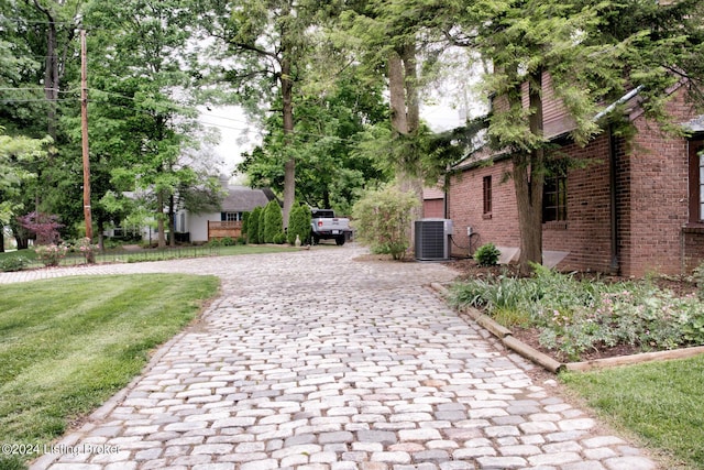 exterior space with decorative driveway and a yard