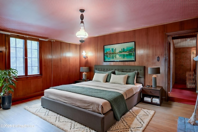 bedroom featuring wooden walls and light wood-style floors