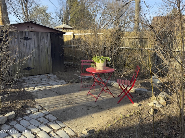 exterior space with a storage shed, an outbuilding, fence, and a patio