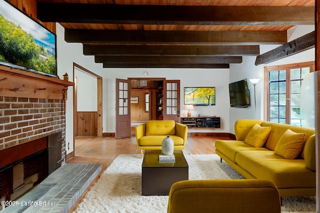 living room featuring beam ceiling, a brick fireplace, and hardwood / wood-style floors