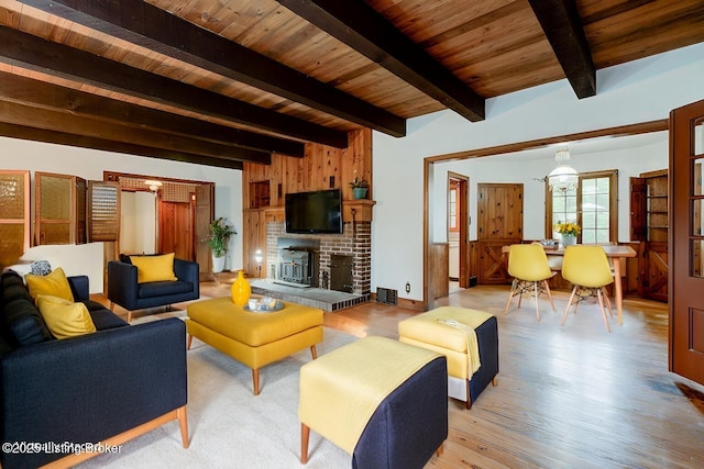 living area featuring beamed ceiling, wooden ceiling, a fireplace, and light wood-type flooring