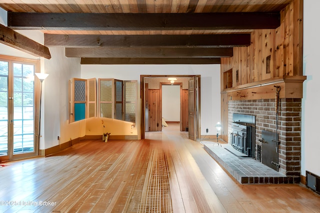 unfurnished living room featuring a wealth of natural light, beamed ceiling, baseboards, and hardwood / wood-style floors