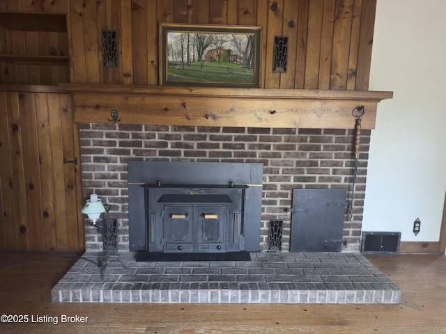 room details featuring visible vents, wood finished floors, and a wood stove