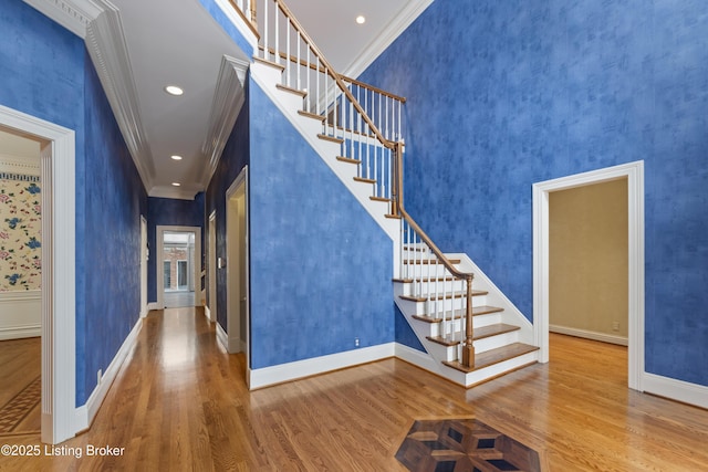 foyer entrance with stairway, ornamental molding, baseboards, and wood finished floors