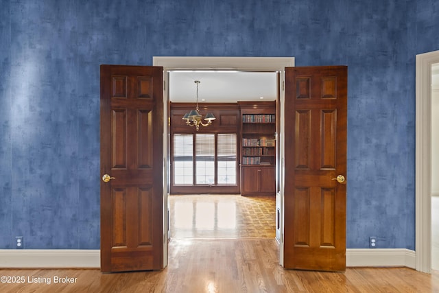 interior space with baseboards, a notable chandelier, and wood finished floors