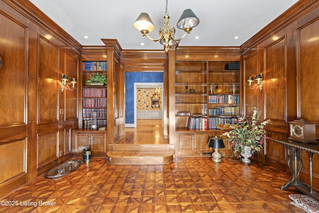 office area featuring a decorative wall, built in features, a chandelier, and ornamental molding