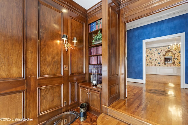 interior details featuring parquet flooring, a decorative wall, crown molding, and a wainscoted wall