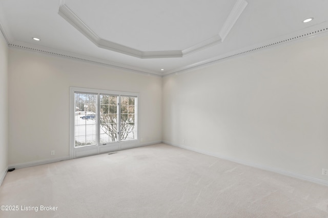 carpeted spare room featuring a raised ceiling, baseboards, and ornamental molding