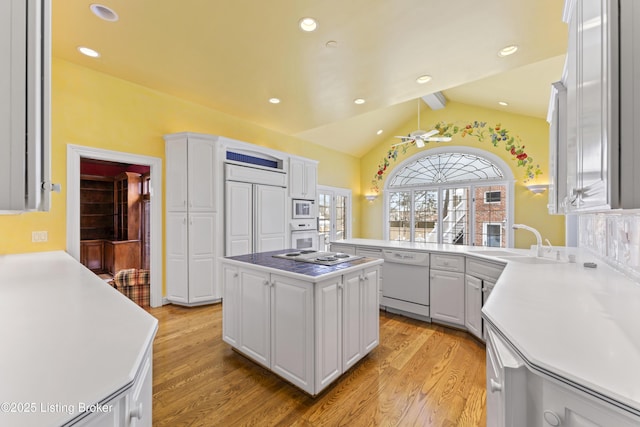 kitchen with white appliances, white cabinets, vaulted ceiling with beams, and a sink