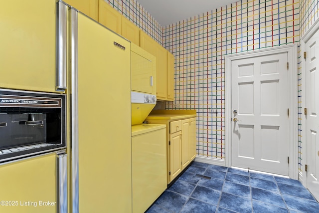 washroom featuring stacked washer / drying machine, tile walls, and laundry area