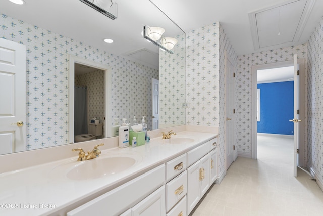 bathroom featuring wallpapered walls, double vanity, toilet, and a sink