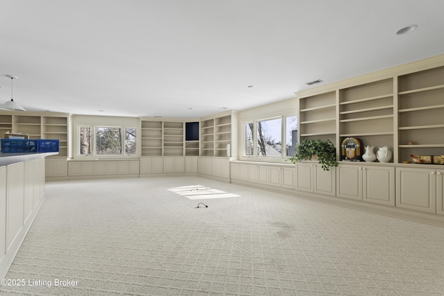 interior space featuring plenty of natural light, light colored carpet, visible vents, and built in shelves