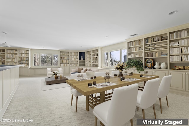 dining space featuring built in features, visible vents, and light colored carpet