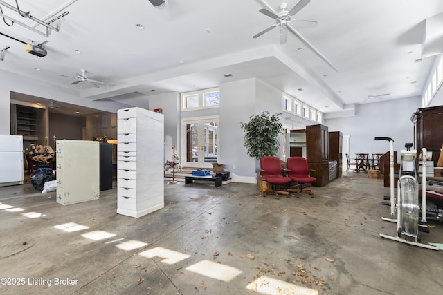 garage featuring baseboards, a garage door opener, ceiling fan, and freestanding refrigerator