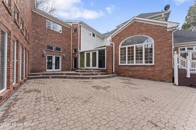 rear view of house with french doors, a patio, brick siding, and entry steps