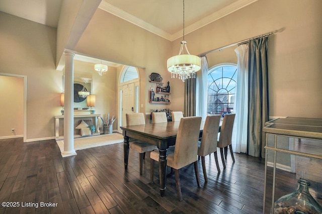 dining area with a towering ceiling, an inviting chandelier, ornate columns, and dark wood-style flooring