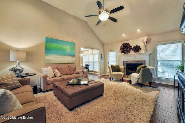 living room featuring a ceiling fan, wood finished floors, baseboards, high vaulted ceiling, and a fireplace