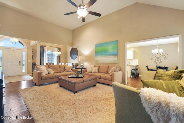 living room with ceiling fan with notable chandelier, high vaulted ceiling, baseboards, and hardwood / wood-style floors