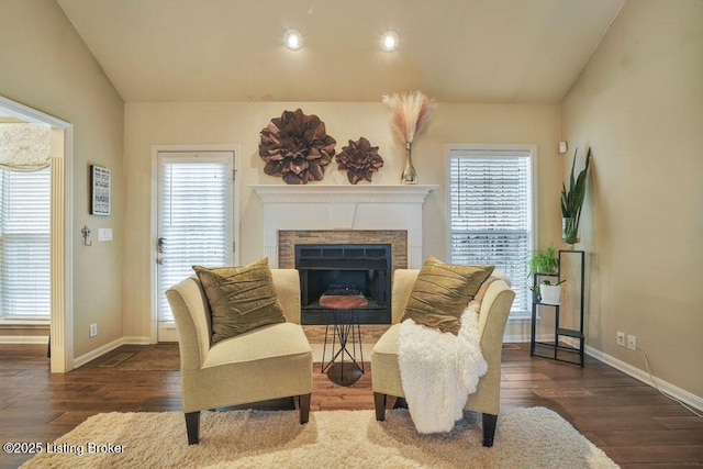 sitting room with vaulted ceiling, a fireplace, and wood finished floors