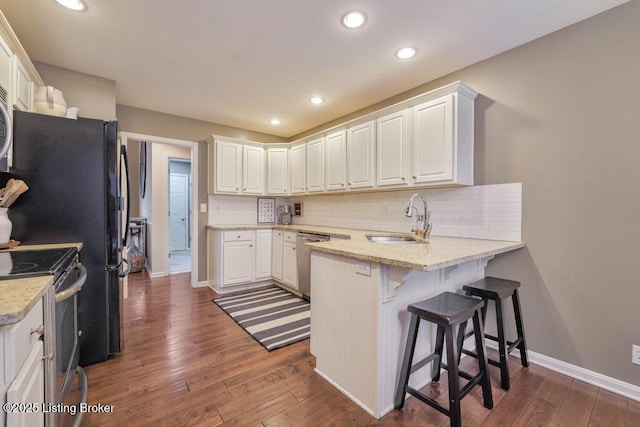 kitchen with white cabinetry, a peninsula, appliances with stainless steel finishes, and a sink