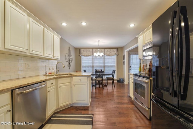 kitchen with a sink, tasteful backsplash, appliances with stainless steel finishes, a peninsula, and dark wood-style flooring