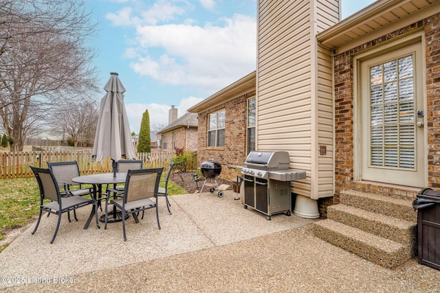 view of patio with outdoor dining area, fence, and grilling area