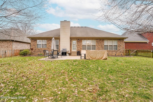 back of house with brick siding, a lawn, a chimney, a fenced backyard, and a patio area