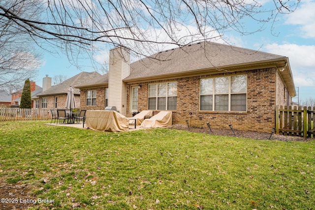 back of property featuring brick siding, fence, a chimney, a yard, and a patio area