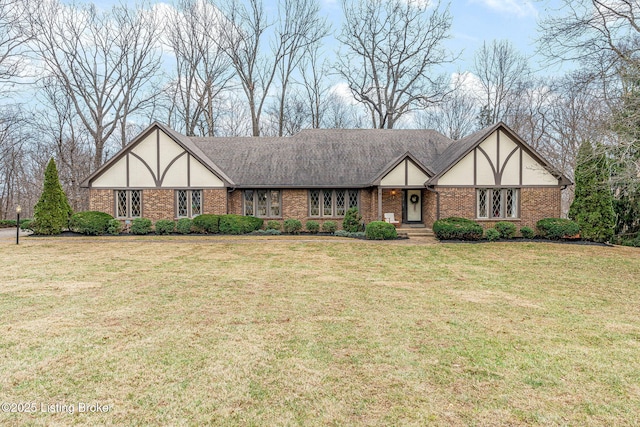 tudor house with roof with shingles, a front lawn, and stucco siding