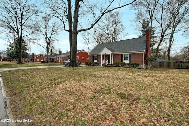 view of front facade with a chimney, fence, a front lawn, and brick siding