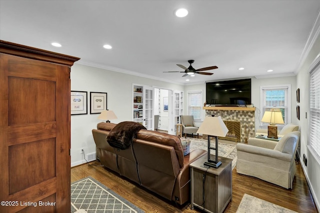 living room with baseboards, a tiled fireplace, ornamental molding, and dark wood-style flooring