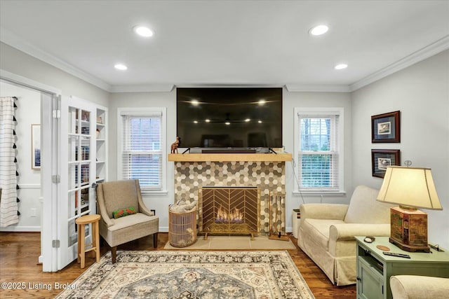 sitting room with a tile fireplace, crown molding, recessed lighting, and wood finished floors