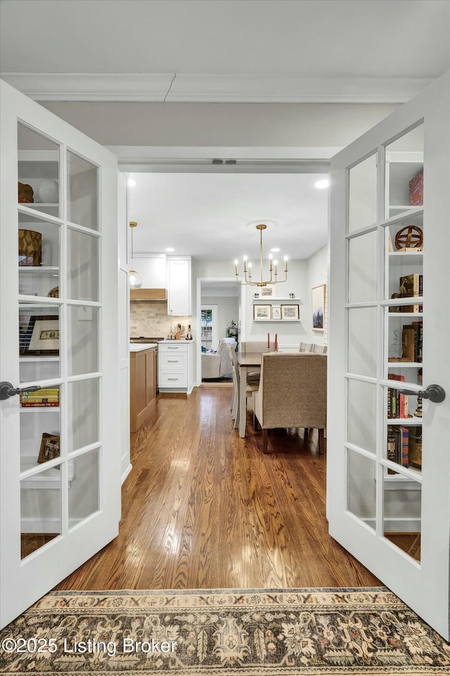 interior space with ornamental molding, wood finished floors, and a notable chandelier