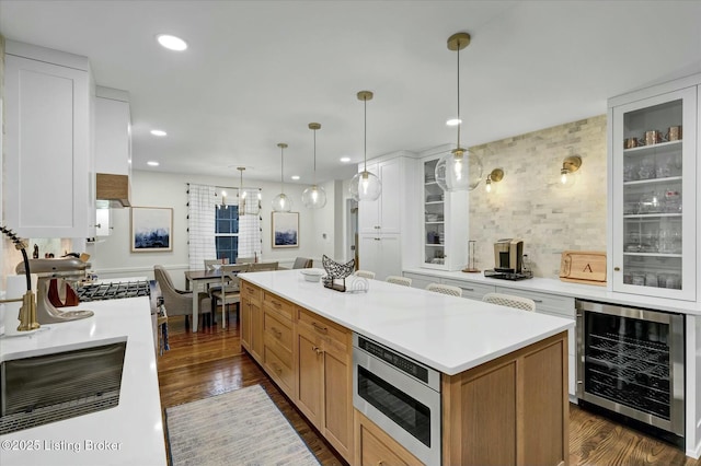 kitchen featuring wine cooler, dark wood-style flooring, light countertops, stainless steel microwave, and glass insert cabinets