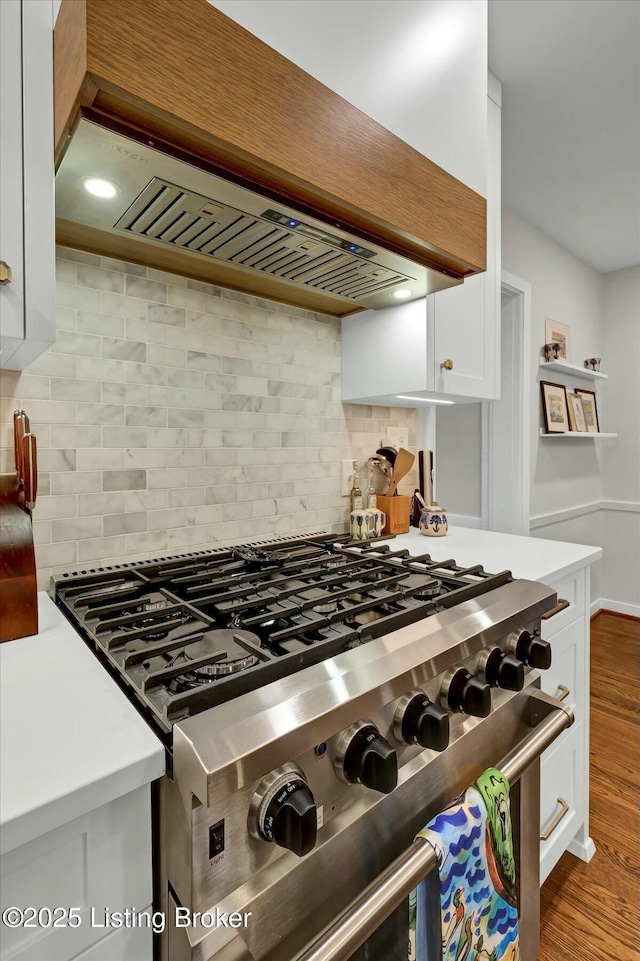 kitchen featuring stainless steel stove, light countertops, custom exhaust hood, and white cabinetry