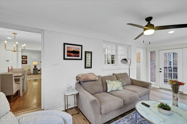 living area with light wood-style floors and ceiling fan with notable chandelier