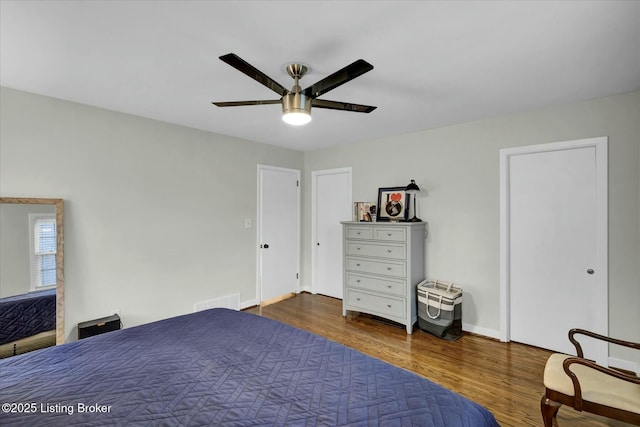 unfurnished bedroom featuring baseboards, ceiling fan, visible vents, and wood finished floors