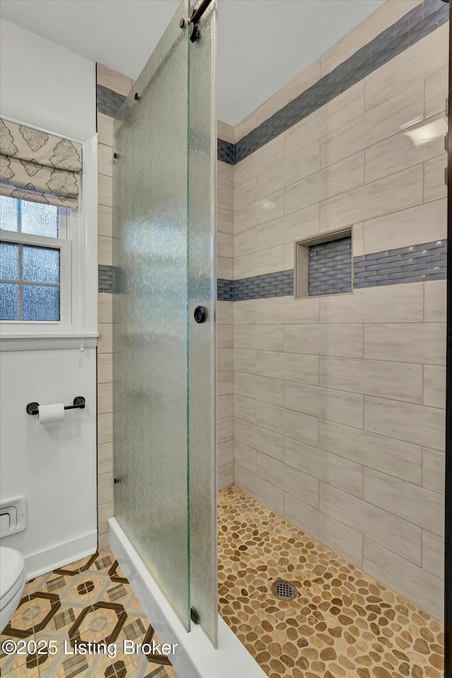 full bath with toilet, a shower stall, and baseboards