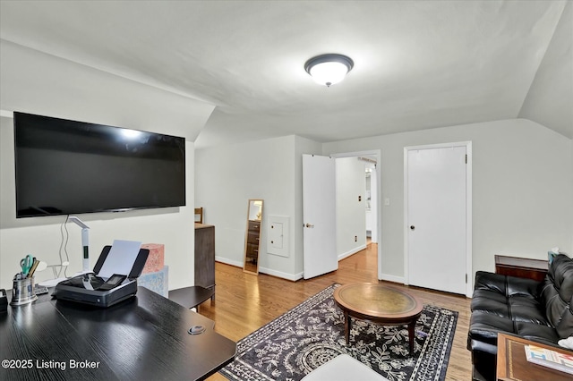 living room featuring baseboards, vaulted ceiling, and wood finished floors