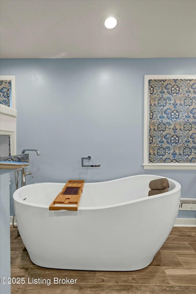 bathroom with wood finish floors, a soaking tub, and recessed lighting