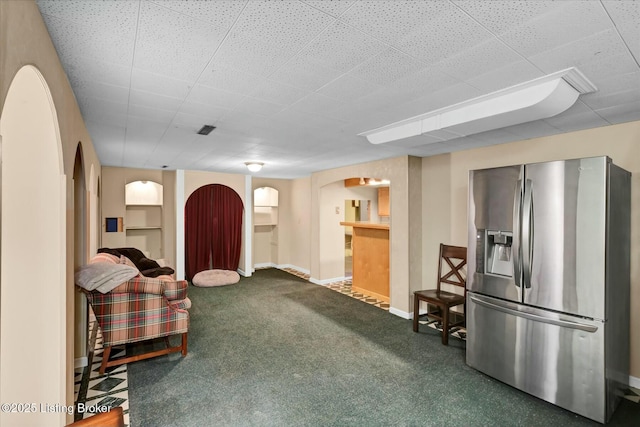 interior space with carpet floors, arched walkways, baseboards, and stainless steel fridge with ice dispenser