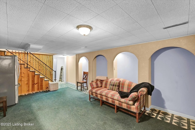 living area with carpet floors, wood walls, stairway, and baseboards