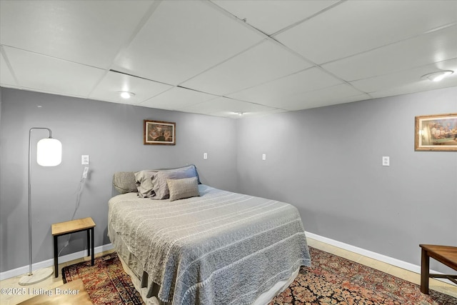 bedroom with a drop ceiling and baseboards