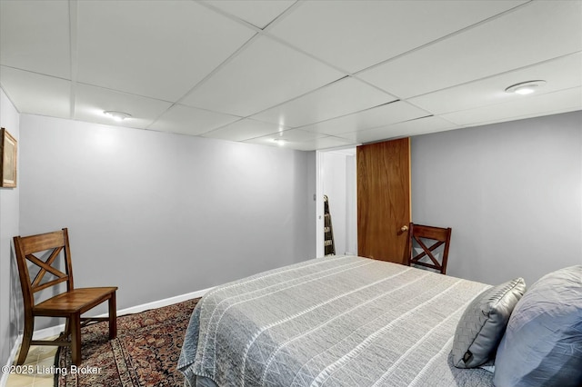 bedroom featuring a paneled ceiling and baseboards