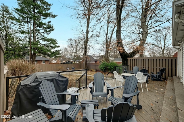 wooden terrace featuring outdoor dining space, fence, and grilling area