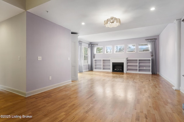 unfurnished living room with light wood-type flooring, a fireplace, and baseboards