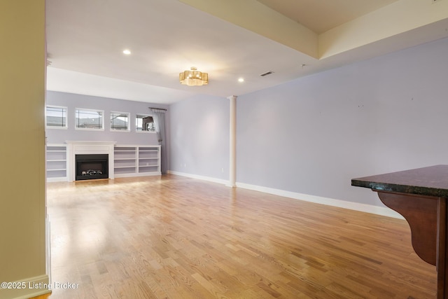 unfurnished living room featuring light wood-type flooring, a fireplace, visible vents, and baseboards