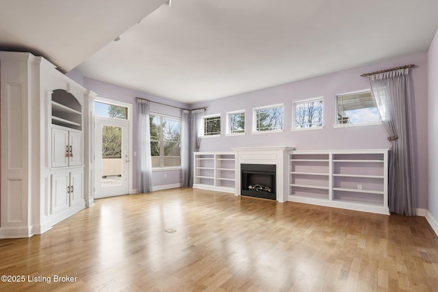 unfurnished living room featuring light wood-style flooring, a fireplace, and baseboards